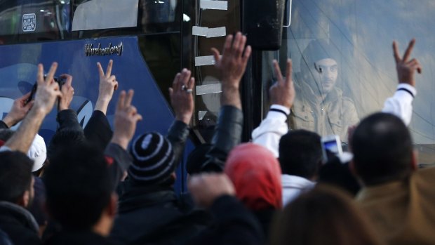 Syrian and Lebanese wave and flash victory signs as convoys carrying wounded Syrian opposition fighters leave the Lebanese border crossing point of Masnaa, on Monday.