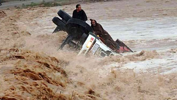 Clinging to life: Driver and passenger sit on a truck stranded in flood waters in the southern region of Ouarzazate in Morocco.