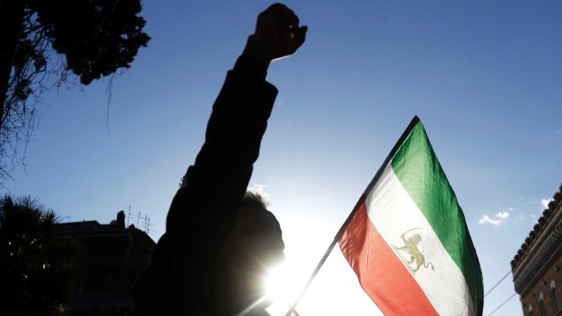 A demonstrator holds the flag of monarchy-era Iran outside the Iranian embassy in Rome.