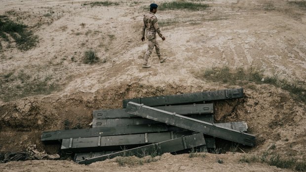 An Iraqi army soldier walks past discarded empty rocket boxes outside Makhmour in March.