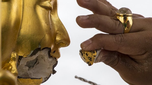 A craftsman fixes the statue of Hindu god Brahma after it was damaged during the deadly blast at the Erawan shrine.