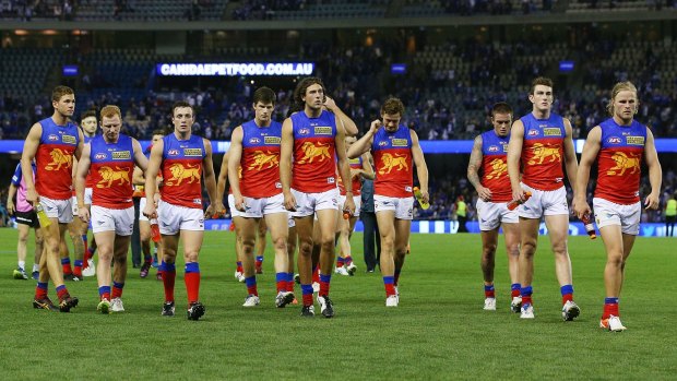 A dejected Lions squad walks off the field after their loss to North Melbourne.
