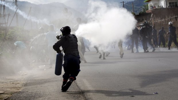 A riot police officer sprays teargas on protesters in Bujumbura.