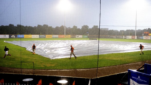 Players and officials put the covers on as rain hits Narrabundah Ballpark
