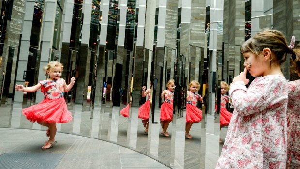 Sage McCrabb and Emerald McMillan test out the maze of mirrors in Semicircular Space, in Federation Court at the National Gallery of Victoria.