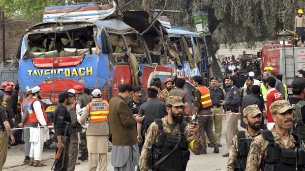 Pakistani soldiers and volunteers surround the bus after the explosion.
