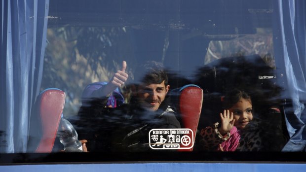 Syrian civilians wave from a bus leaving the Waer neighbourhood of the central city of Homs, Syria, on Wednesday.