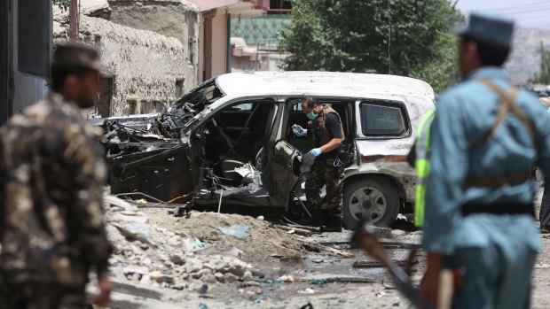 Afghan security personnel inspect a damaged vehicle at the site of a suicide attack that targeted a NATO convoy in Kabul earlier this month. 