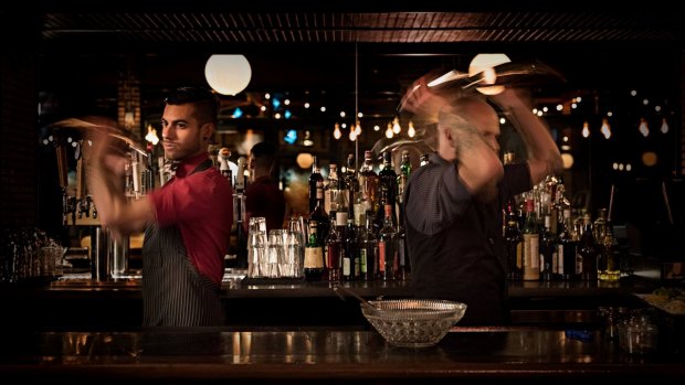 Bartenders mixing cocktails behind the bar at Punch Bowl Social.