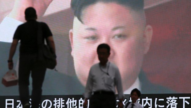 People walk past a TV screen showing an image of North Korean leader Kim Jong-un in Tokyo.