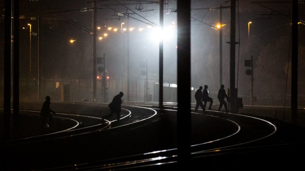 Migrants walk across tracks near the Eurotunnel in Calais in August.