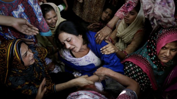 Women try to comfort a mother who lost her son in the attack.