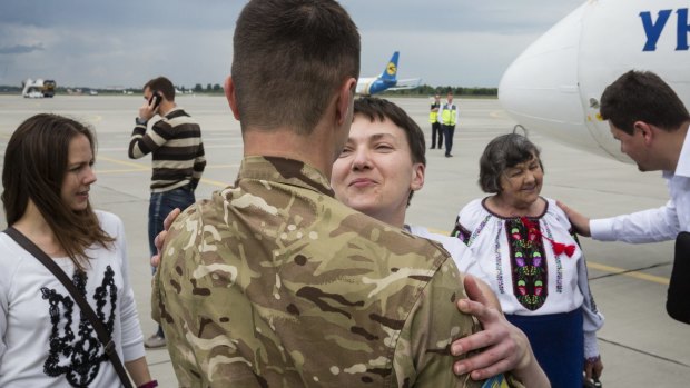 Ukrainian pilot Nadiya Savchenko (centre) is greeted by a serviceman of the Aidar battalion upon her arrival as her sister Vera (left) and her mother, Maria (right) stand behind her at Boryspil Airport outside Kiev, Ukraine.
