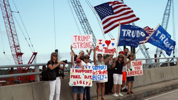 Supporters of US President Donald Trump stand on the bridge to his Mar-a-Lago estate in Florida, as his motorcade passes on Saturday.