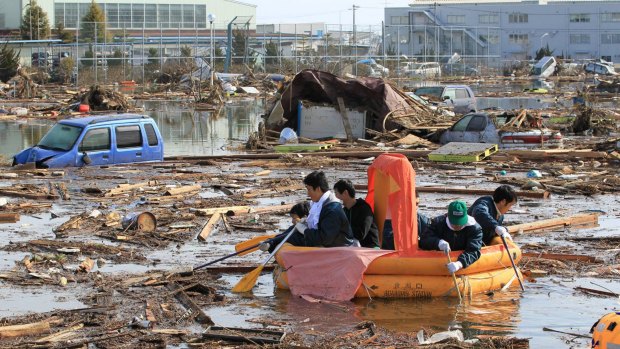 Students use a rubber raft to get food from their dormitory that submerged following the catastrophic earthquake and tsunami.