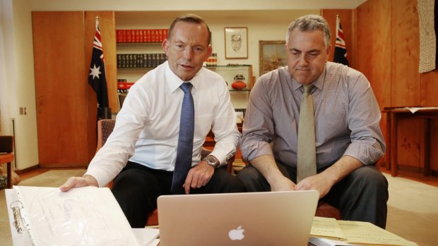 Prime Minister Tony Abbott poses with Treasurer Joe Hockey as they look through the 2015 budget.