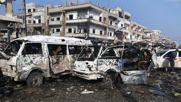 People gather at the scene where two blasts exploded in the pro-government neighbourhood of Zahraa, in Homs Syria, on Sunday.