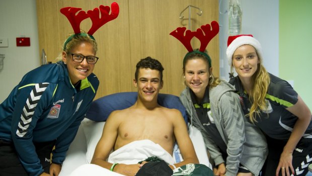 Canberra United players Chantel Jones, Sally Rojahn and Grace Field handed out Christmas gifts at Canberra Hospital on Thursday. They are pictured with patient Jeremy Bridger.