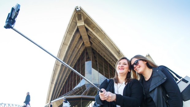 Anna Stahl from Germany and Jennifer Himryd from Sweden use a selfie stick on the steps of the Sydney Opera House.