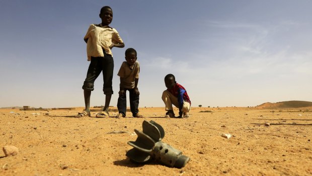 Children stand near the fin of a mortar at the al-Abbasi camp for internally displaced persons in Sudan's Darfur region.