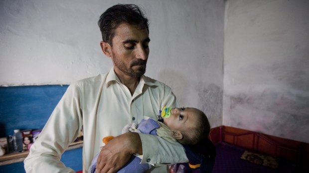 Eight-month-old Sufiyan Qadir carried by his father Noor Qadir, 33, at his house in the city of Peshawar. Qadir has no doubt Peshawar's rats are turning into killers. 