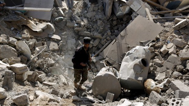 A police trooper walks through a crater left by an air strike on houses near Sanaa Airport.