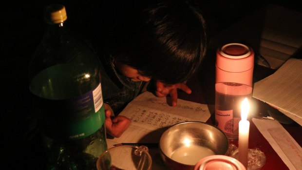 Xu Yuanyuan doing her homework by candlelight at Picun Village in Beijing.