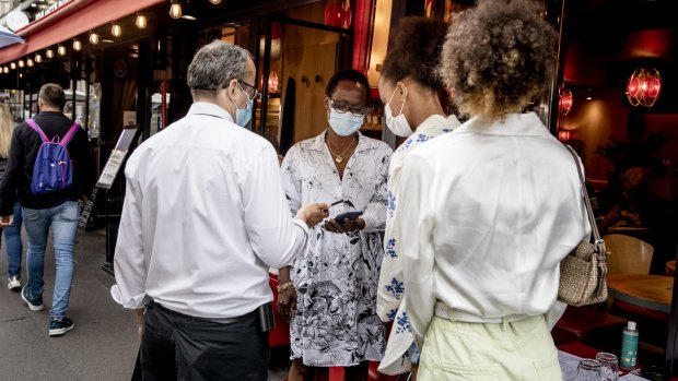 Women show their health passes to a waiter in Paris early this month.