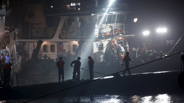 Rescue workers atop the sunken ship, searching through the night. 