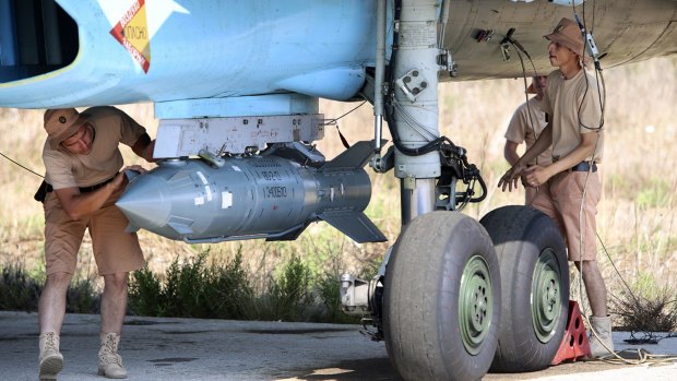 Russian military support crew attach a satellite-guided bomb to a jet fighter in Syria on Saturday. 