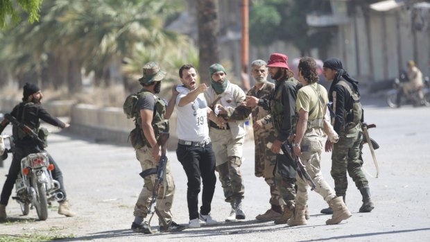 Members of the Army of Conquest, a coalition of Islamist rebel groups, detain a man suspected of being a member of forces loyal to the Syrian regime in Ariha.