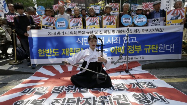 South Korean university student Lee Ye-in performs on a Japanese rising sun flag in Seoul during a rally to denounce Japanese Prime Minister Shinzo Abe's address to a joint session of the US Congress.  