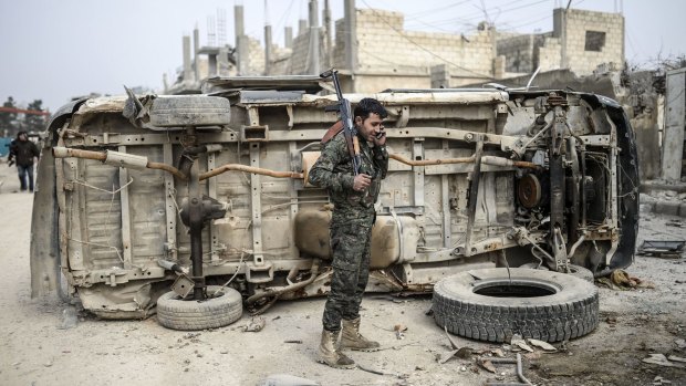 A Kurdish fighter talks on the phone in the centre of Kobane.