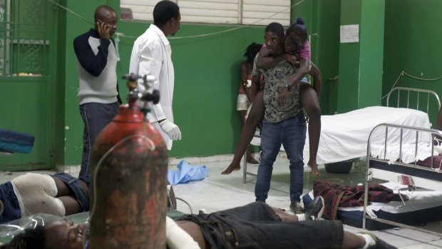 An injured woman is carried by a friend in the emergency room of the General Hospital in Port-au-Prince, Haiti, after the carnival float accident. 