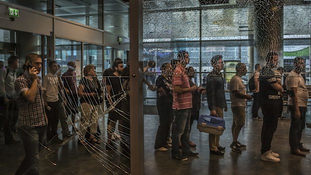 Passengers line up at a security checkpoint  near broken glass in the international terminal at  Ataturk Airport after Tuesday night's attack.