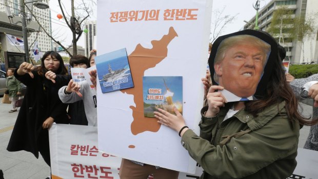 A South Korean protester holds a mask of US President Donald Trump and a Korean Peninsula map during a rally against US deployment in the region outside the US embassy in Seoul.