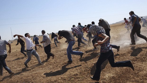 Kurdish protesters at the border with Syria flee from Turkish teargas after trying to watch the fighting in the border town of Kobane in October 2014.