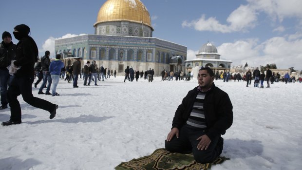 A man prays in the snow.