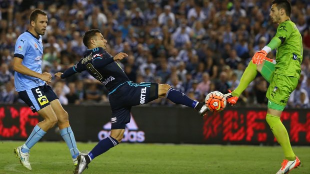 Kosta Barbarouses of Melbourne Victory is challenged by Sydney FC  goalkeeper Vedran Janjetovic.
