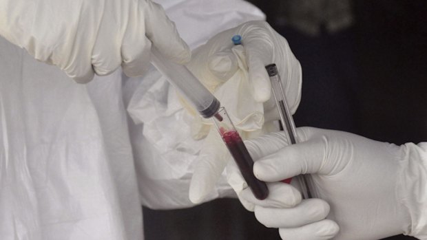 Health workers take a blood specimen from a child to test for the Ebola virus in the district where the 17-year-old had lived. 