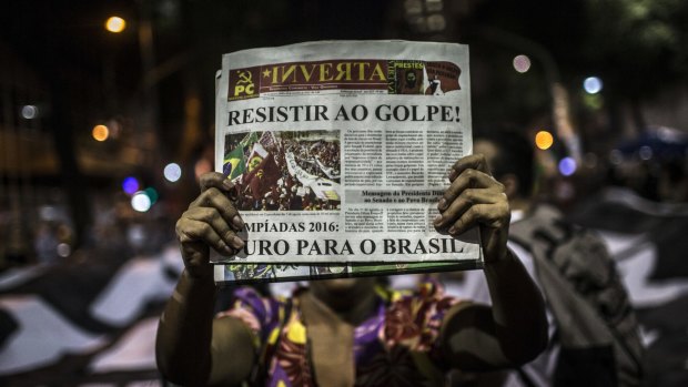 A demonstrator holds a Communist Party publication reading "Resist the Coup", during a protest against the impeachment of Dilma Rousseff in Rio de Janeiro on Monday.