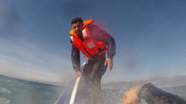 A Turkish Coast Guard officer reaches out to Pelen Hussein, a 20-year-old Syrian migrant.
