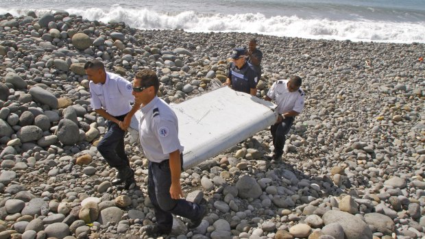 French police officers carry the piece of a wing confirmed as from MH370. 