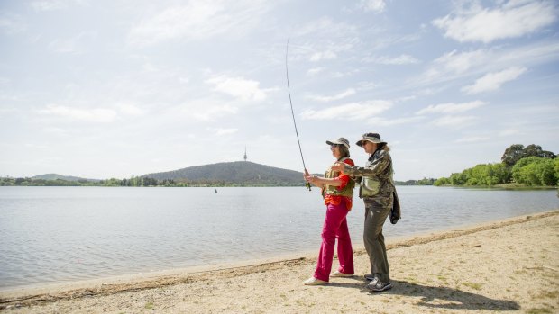 Kerryn Milligan (left) shows Bernadette Bradley how to flyfish on the shore of Lake Burley Griffin.
