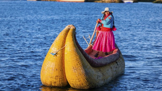 A Peruvian woman sailing between Uros floating islands, Lake Tititcaca.