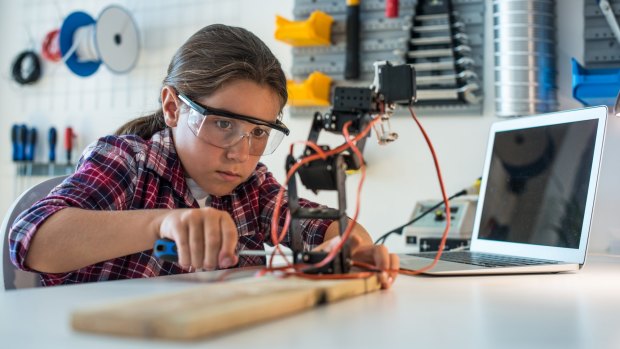 Young girl working in a robotics workshop. 