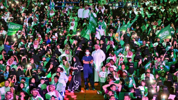In this September 23, 2017 photo released by Saudi Press Agency, SPA, Saudi men and women attend national day ceremonies at the King Fahd stadium in Riyadh, Saudi Arabia. Women will be allowed into sports stadiums as of next year, the kingdom's latest step toward easing rules on gender segregation, but they will only be allowed to sit in the so-called family section.