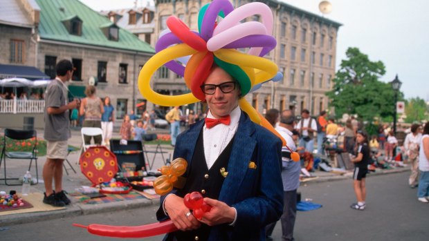 A man wears a balloon hat as he walks past the street vendors at Place Jacques Cartier in Montreal's Old Town.