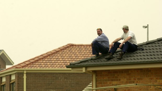 The Armour brothers Mick and Warren sits on their roof on Fairlight street in Dunlop awaiting news of approaching fires during a state of high alert on January 21, 2003.