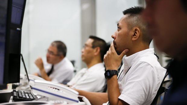 In shock: Employees work in front of computer monitors at a foreign exchange brokerage in Tokyo, Japan, on Friday.